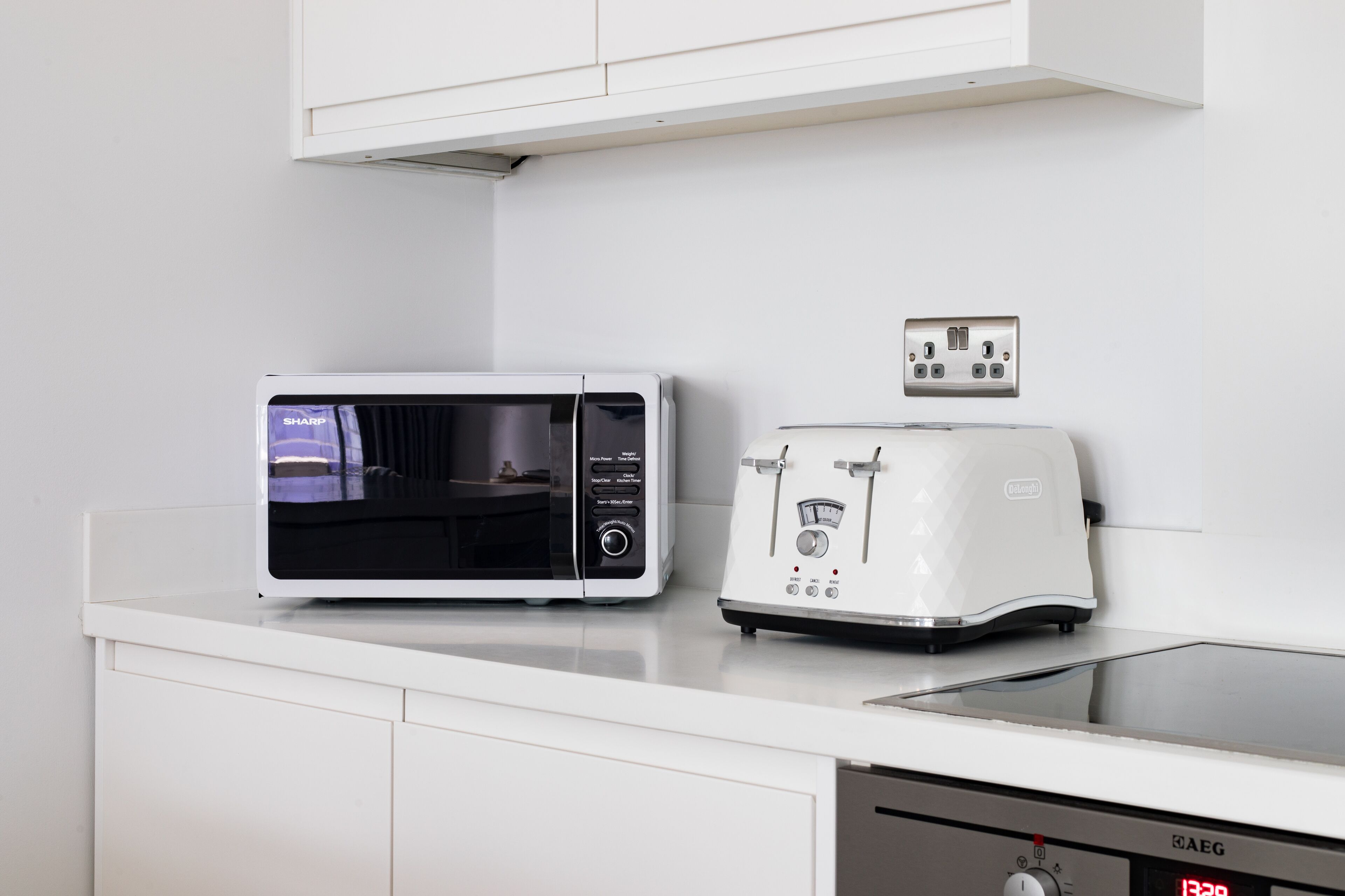 Una cocina con microondas y tostadora sobre una encimera blanca.