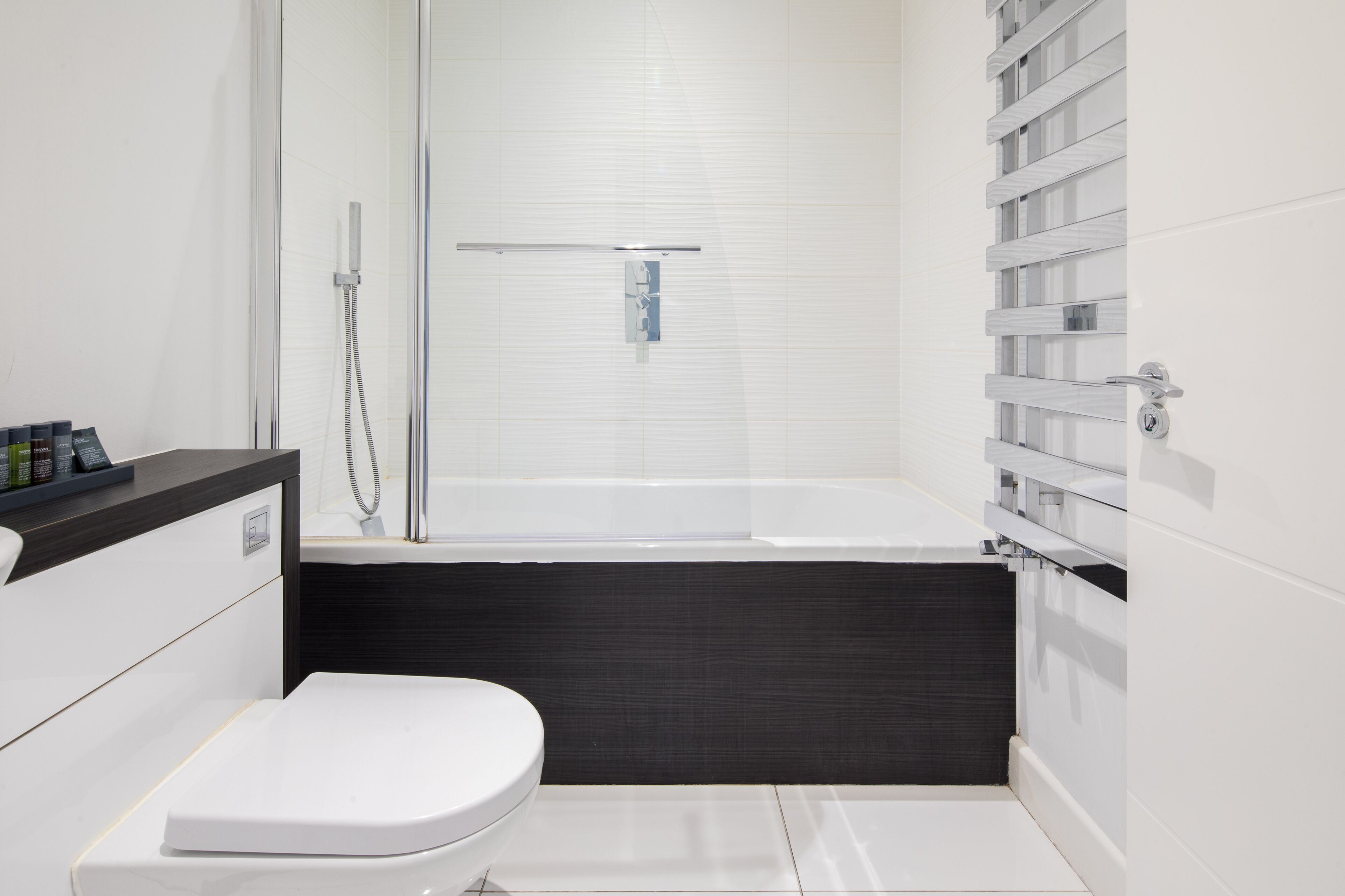 A modern bathroom with a white toilet, a shower enclosure, and a built-in bathtub.