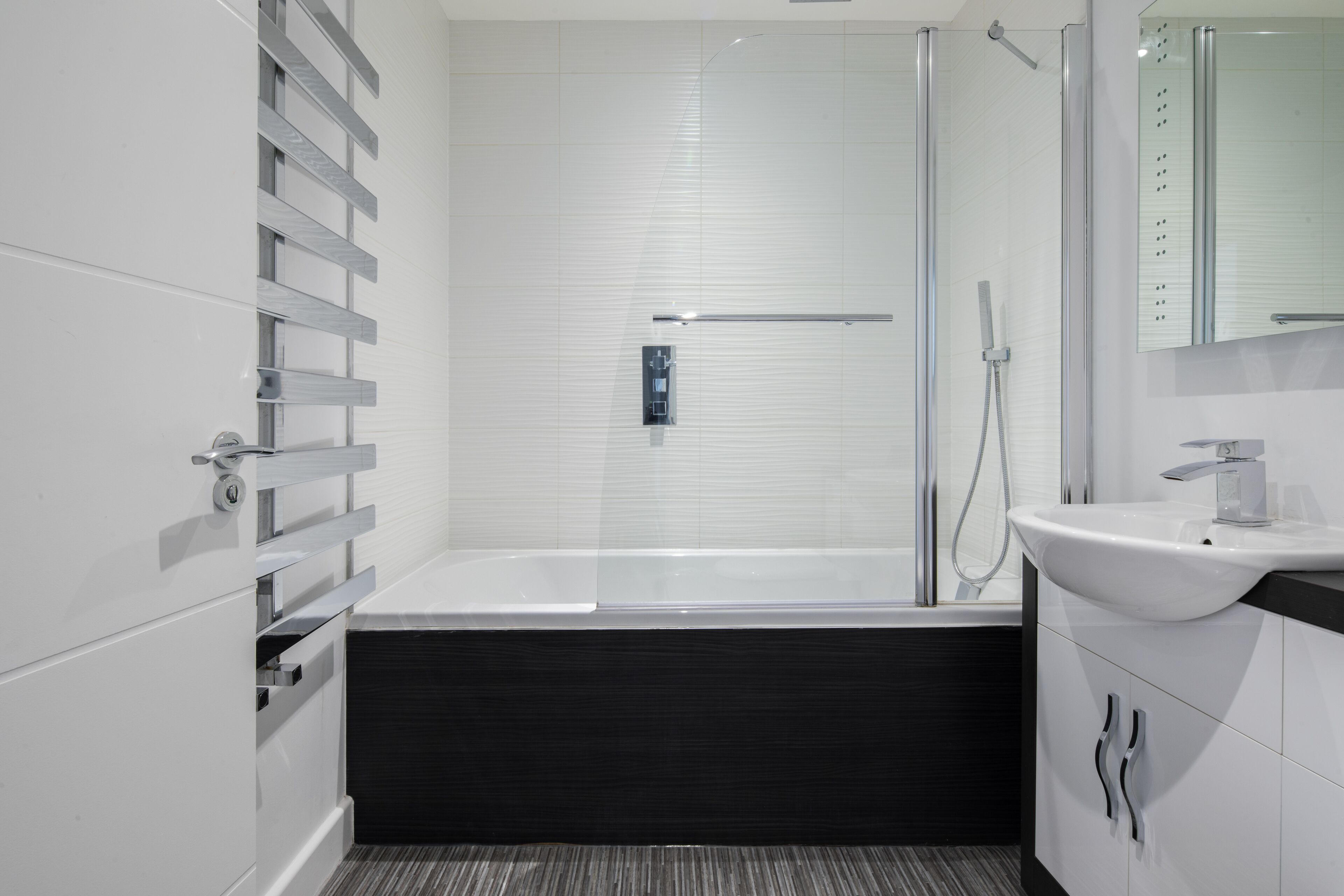 A modern bathroom with a glass shower enclosure, a bathtub, and a vanity with a sink.