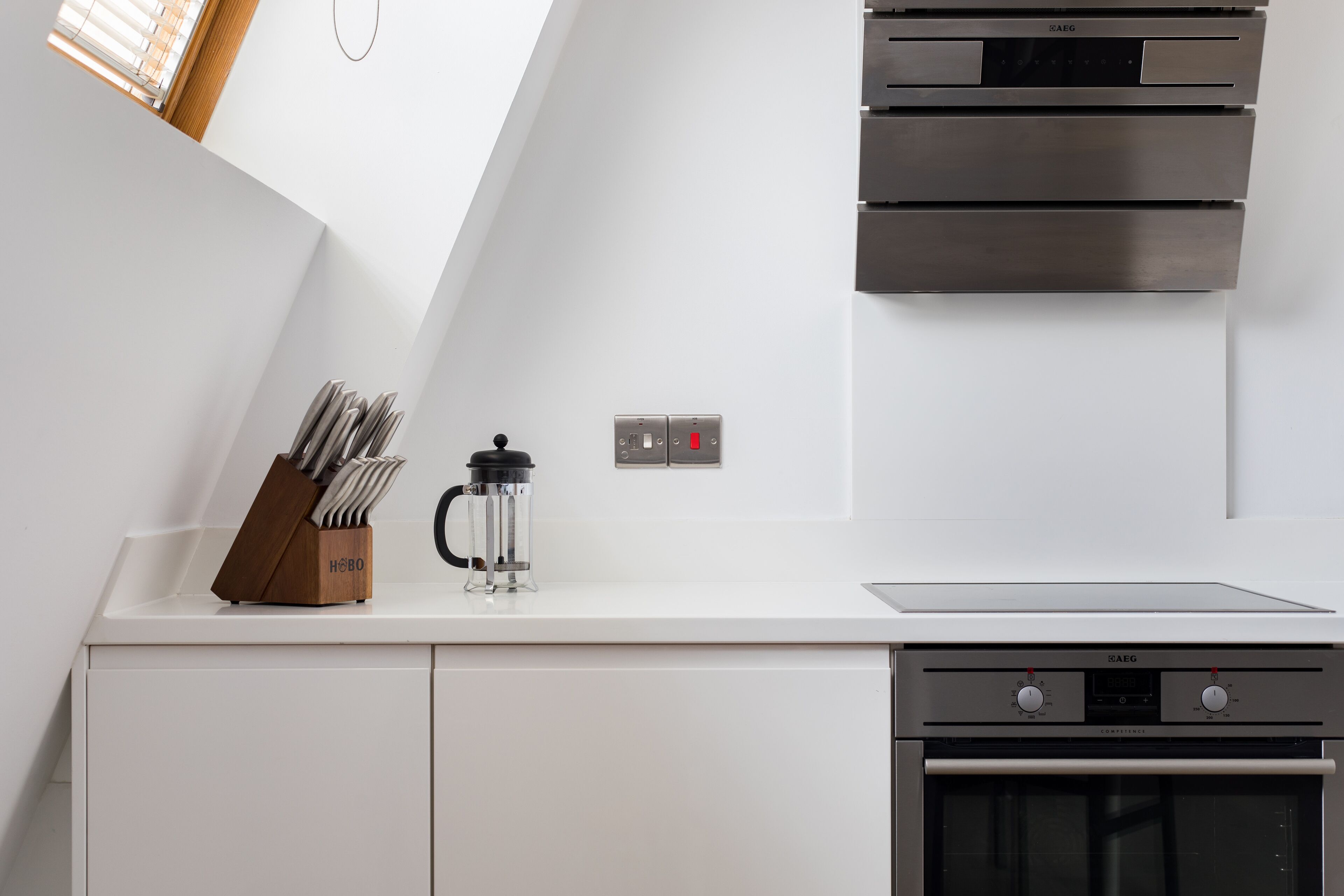 A modern kitchen with a built-in oven, a coffee maker, and a knife block.