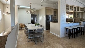 A spacious kitchen with a central island, a dining area with chairs, and a kitchen island with stools. - Oceanfront 4 Bedroom 4.5 Bathroom House on A Street St Augustine (St. Augustine)