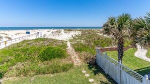 A beach with a white fence, a palm tree, and a clear blue sky. - Oceanfront 4 Bedroom 4.5 Bathroom House on A Street St Augustine (St. Augustine)
