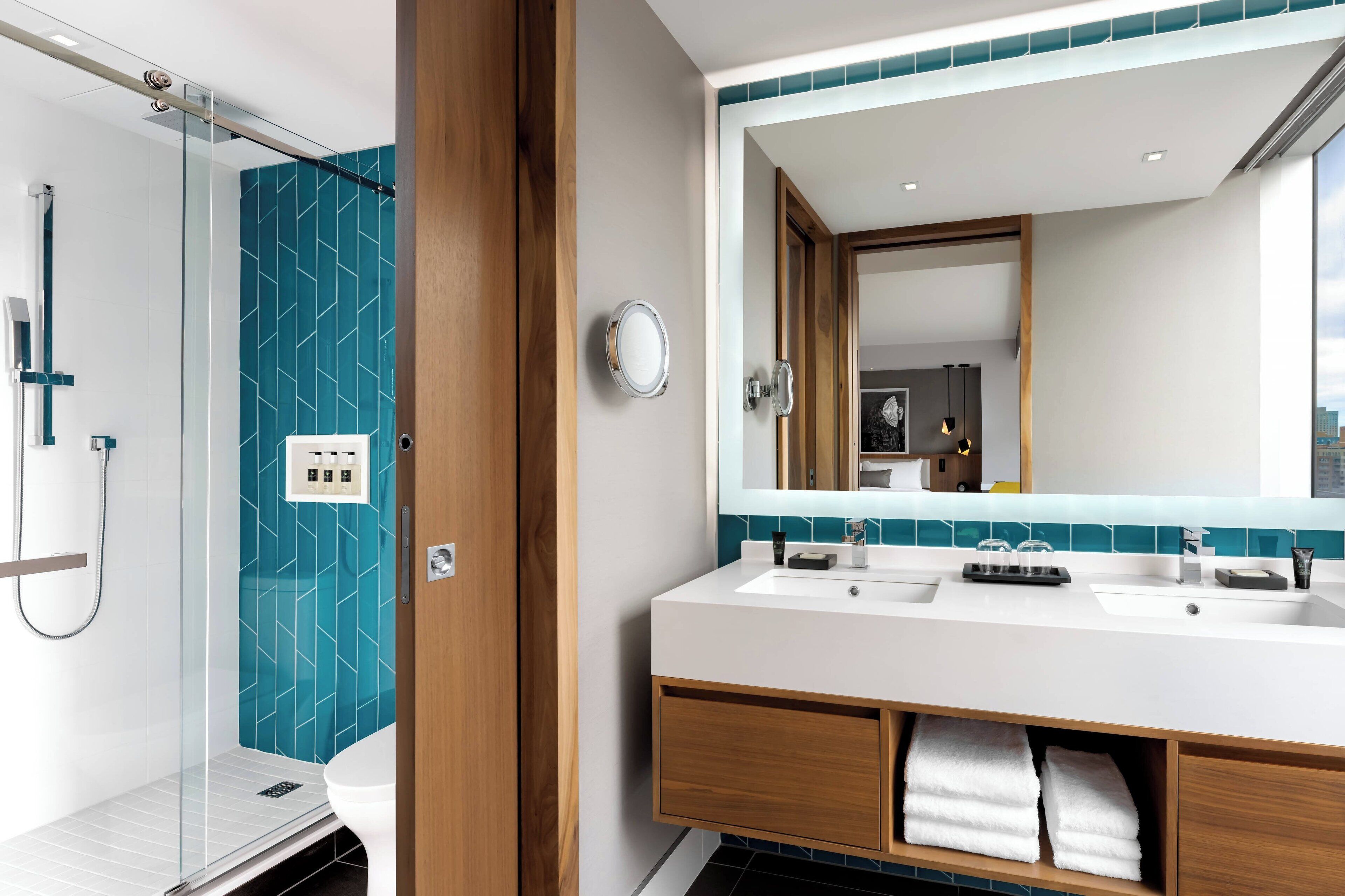 Un baño moderno con cabina de ducha de vidrio, un lavamanos blanco con espejo y un reverso de azulejos azules.