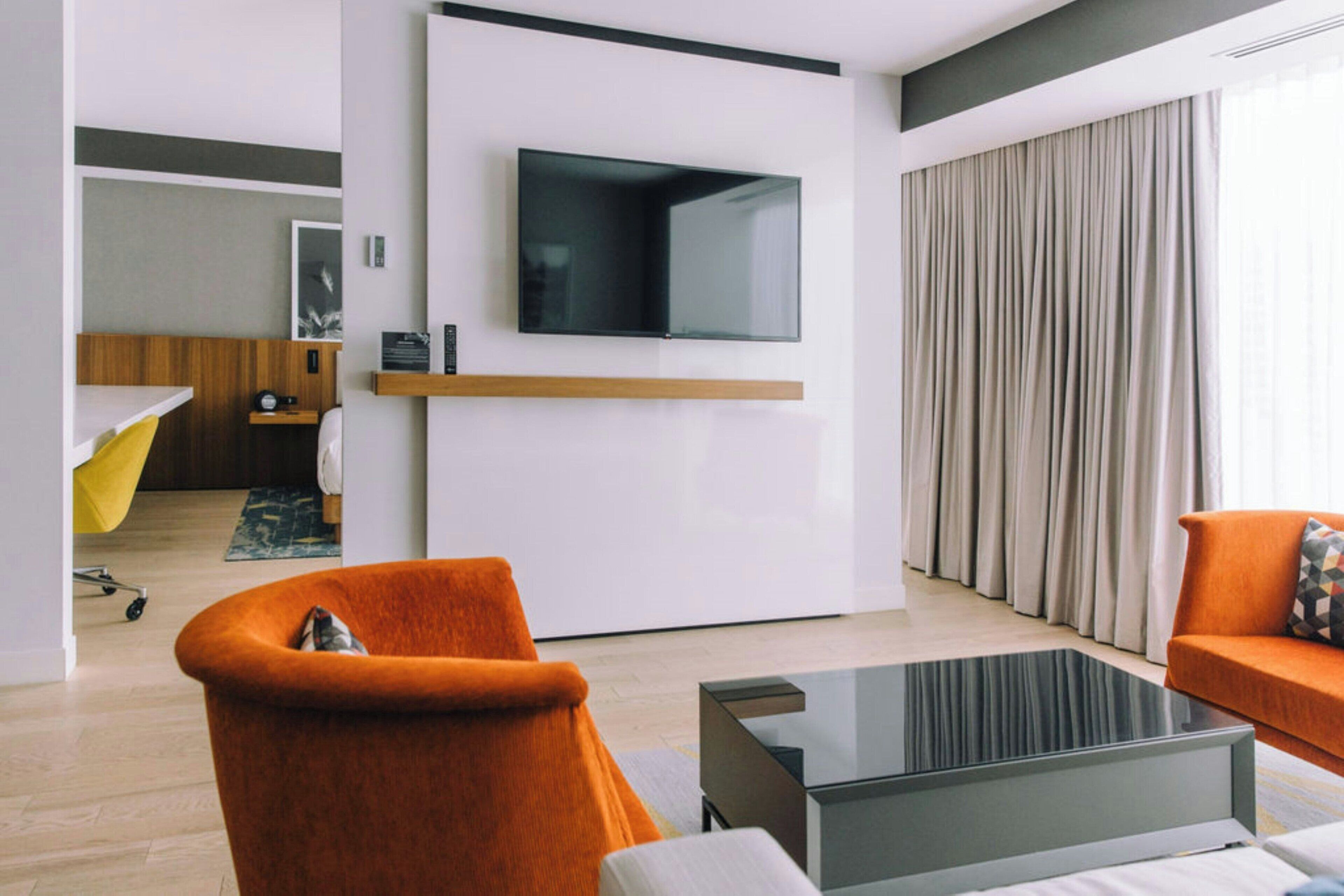 A modern living room with a flat-screen TV mounted on the wall, a sofa, and a coffee table.