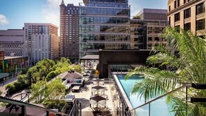 A rooftop pool area with outdoor seating and a view of surrounding buildings. - Humaniti Hotel Montreal, Autograph Collection (Montreal)