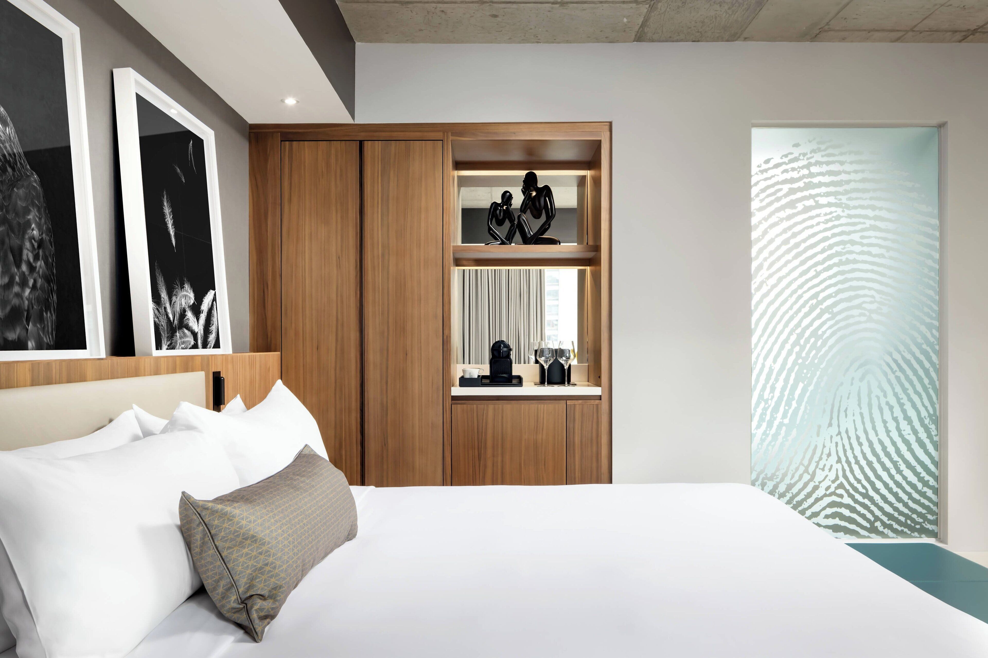 Una habitación de hotel moderna con una cama grande, un armario de madera y un panel decorativo en la pared.