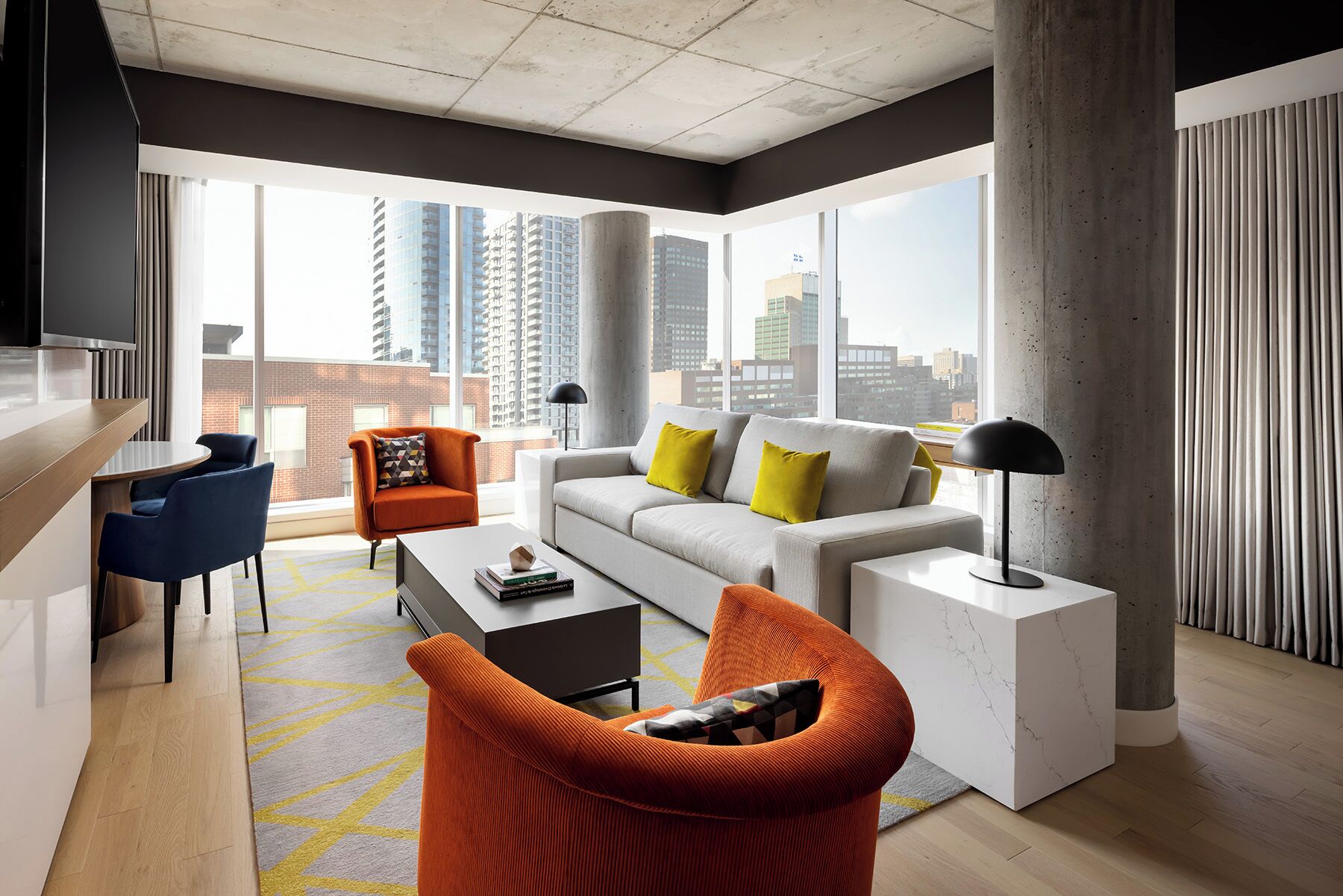 A modern living room with a sofa, armchairs, a coffee table, and a TV.