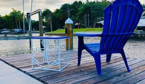 A wooden deck with a blue chair and a white metal table. - Cozy Florida Waterfront Home (Sarasota)