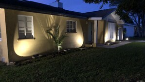 A house with a well-maintained lawn, a small palm tree, and a porch with a door. - Cozy Florida Waterfront Home (Sarasota)