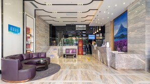 A modern hotel lobby with a reception desk, seating area, and a view of the outdoors. - Shenzhen Qianhai Times City Branch of Lavande Hotel (Shenzhen)