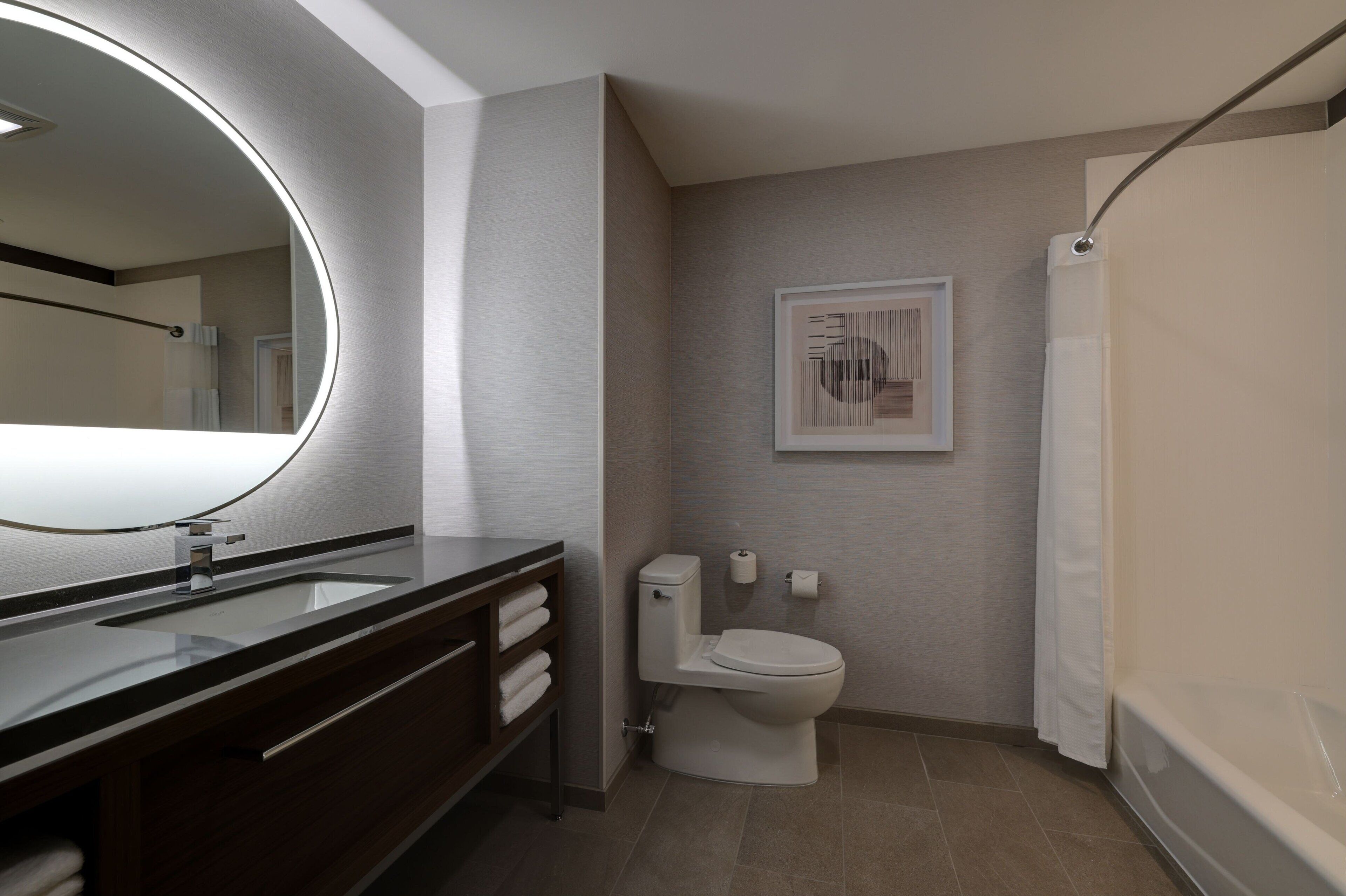 A modern bathroom with a large mirror, a toilet, and a shower.