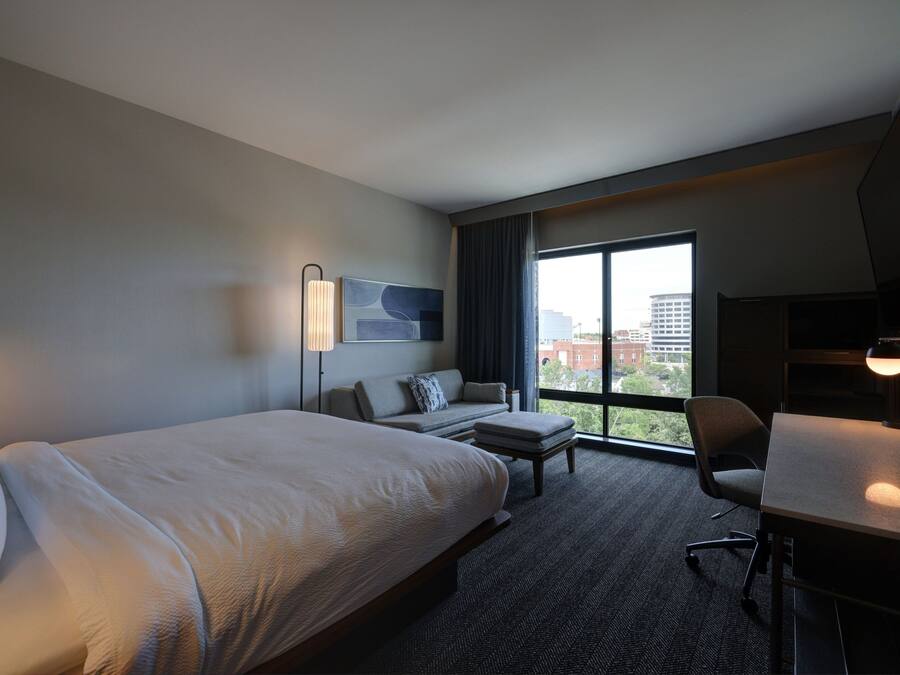 A hotel room with a large bed, a sofa, a desk, and a TV.