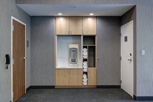 Habitación de hotel con un armario de madera, un calefactor empotrado y un estante con toallas enrolladas.