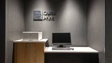 Um espaço de escritório moderno com uma impressora, um computador de mesa e um aviso que diz 'Quick Print'.
