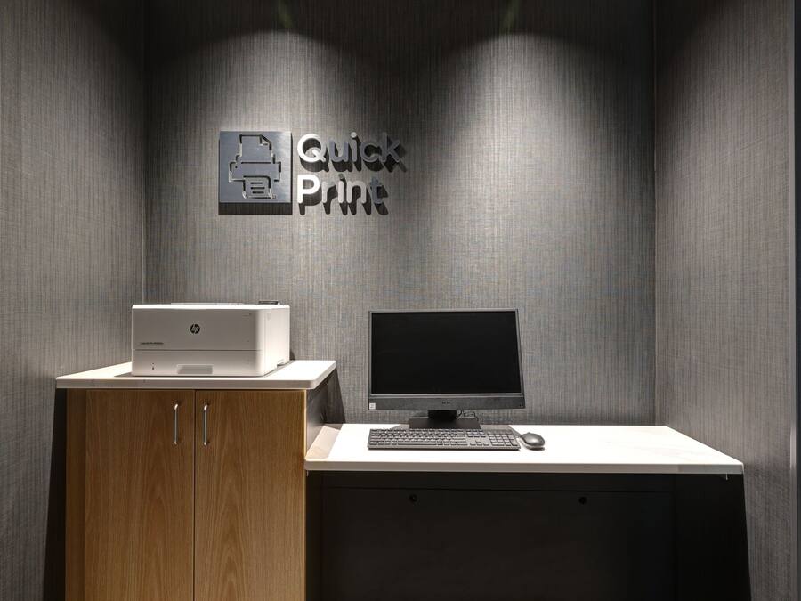 Um espaço de escritório moderno com uma impressora, um computador de mesa e um aviso que diz 'Quick Print'.