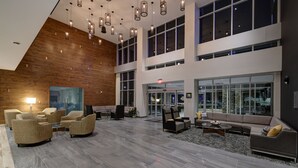 Un lobby espacioso con techo alto, muebles modernos y amplias ventanas que ofrecen vistas a la ciudad.