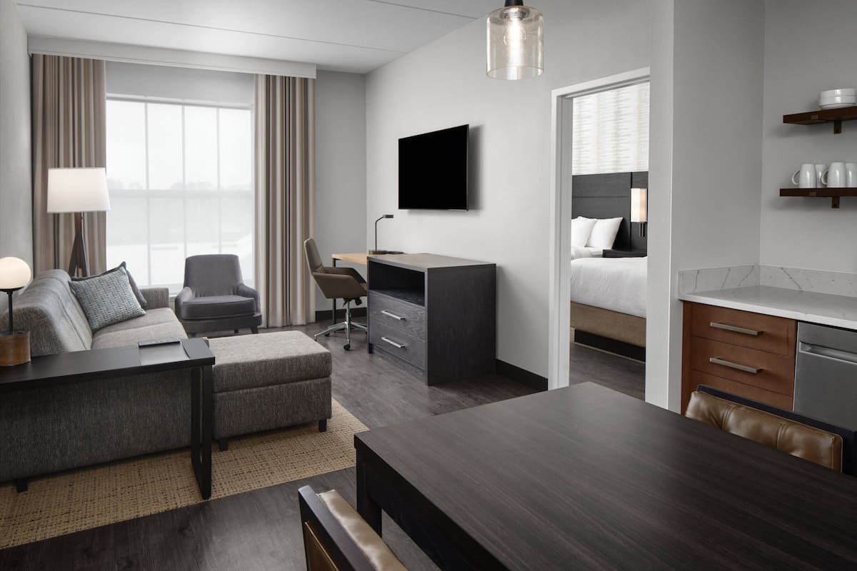 Una habitación de hotel moderna con sofá, escritorio y kitchenette.