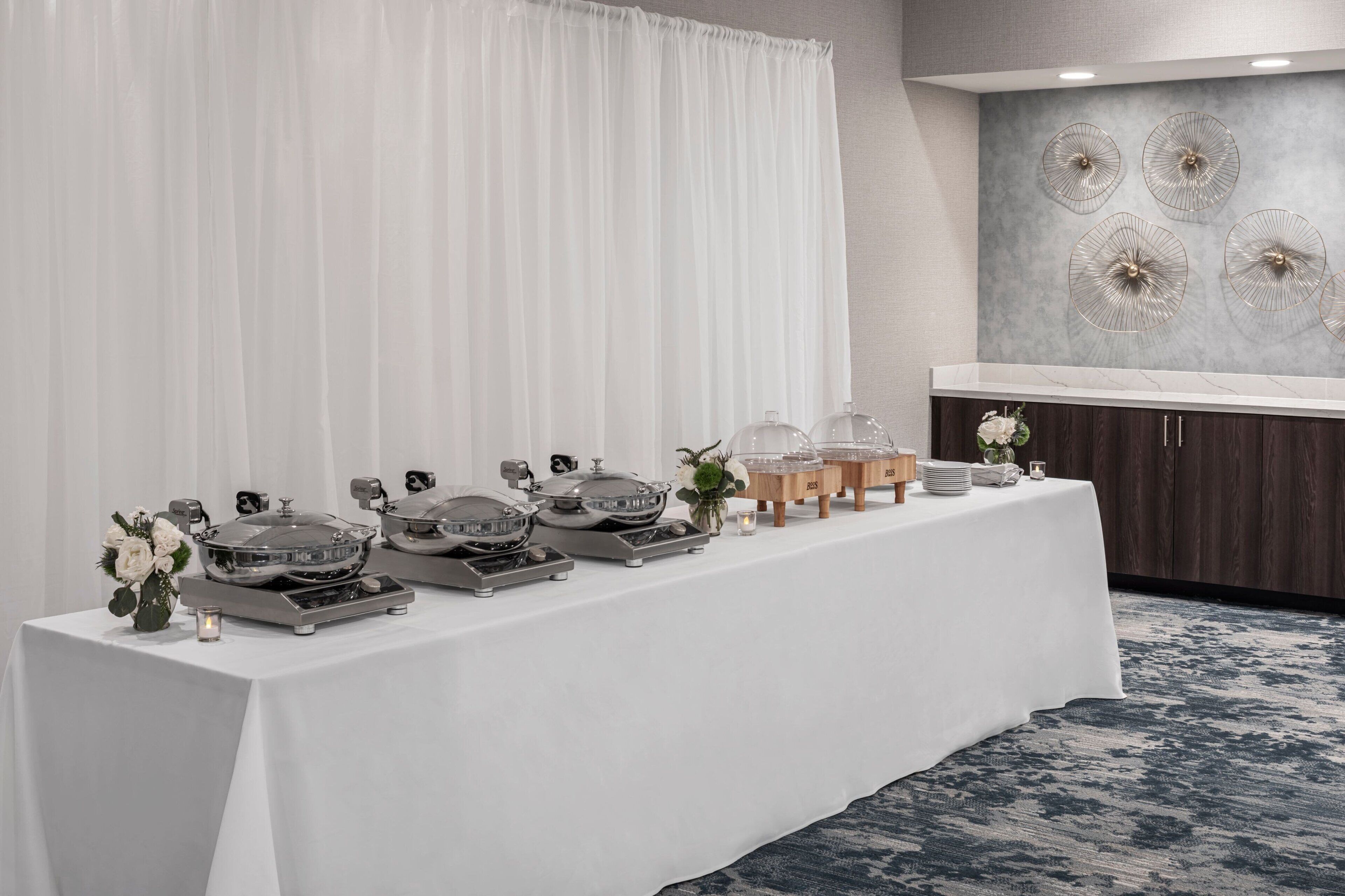 Una mesa de buffet con alimentos y una pared decorativa con diseños circulares.