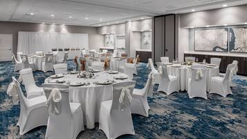 A conference room with round tables, white chairs, and a blue carpet.