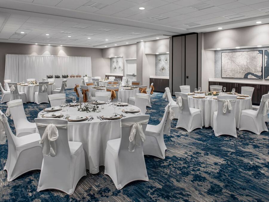 A conference room with round tables, white chairs, and a blue carpet.