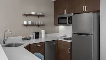 Una cocina moderna con electrodomésticos de acero inoxidable, armarios de madera y encimeras de mármol.