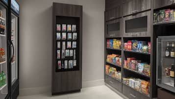 A self-service kiosk with various packaged goods and a refrigerated section with beverages.