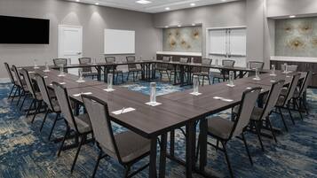 A conference room with a long table, chairs, and a carpeted floor.