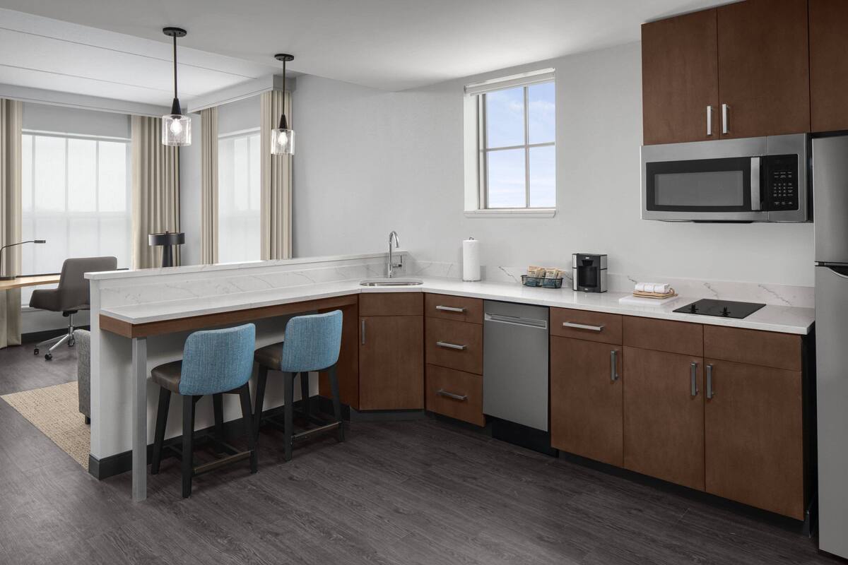 Una cocina moderna con armarios de madera, microondas integrado y lavavajillas.