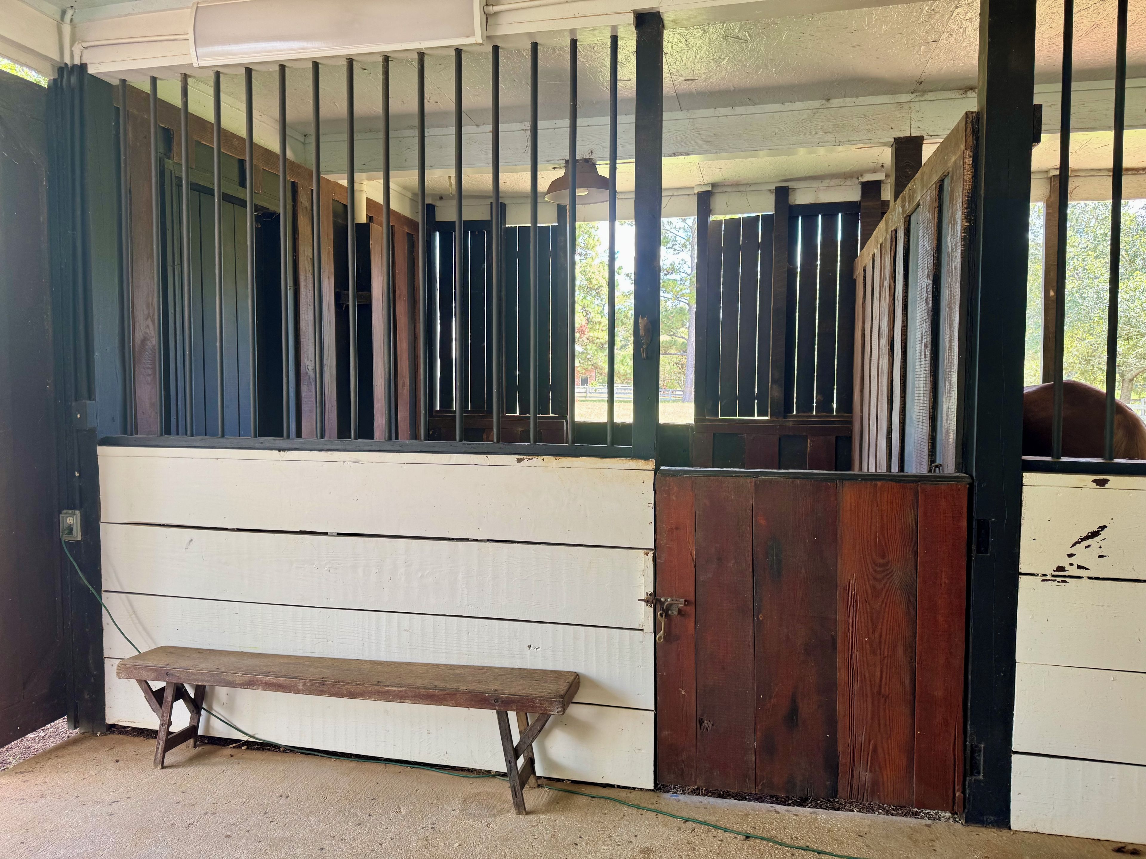 Une étable avec des boxes en bois, un banc et une porte.