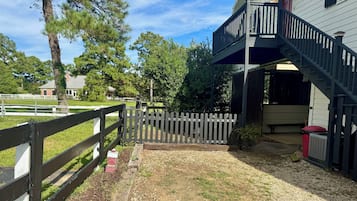 A wooden fence, gravel path, and a building with a balcony.