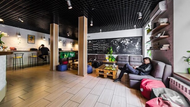 Un área lounge moderna con bar, asientos y una pared de pizarra con escritura.