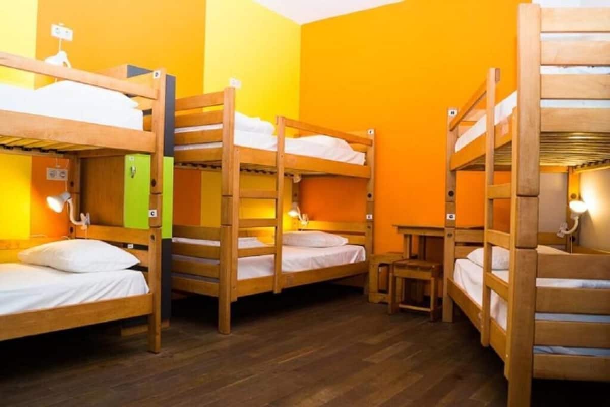 A dormitory room with bunk beds, a small table, and a green cabinet.