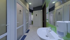Baño de hotel con un lavamanos grande, espejos y dispensadores de gel hidroalcohólico.