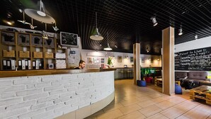 Un área de recepción moderna con un mostrador de ladrillo blanco, iluminación sobre la cabeza y una pizarra con mensajes motivacionales.