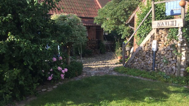 Een huis van baksteen met een rood pannendak, een stenen muur met een bord waarop 