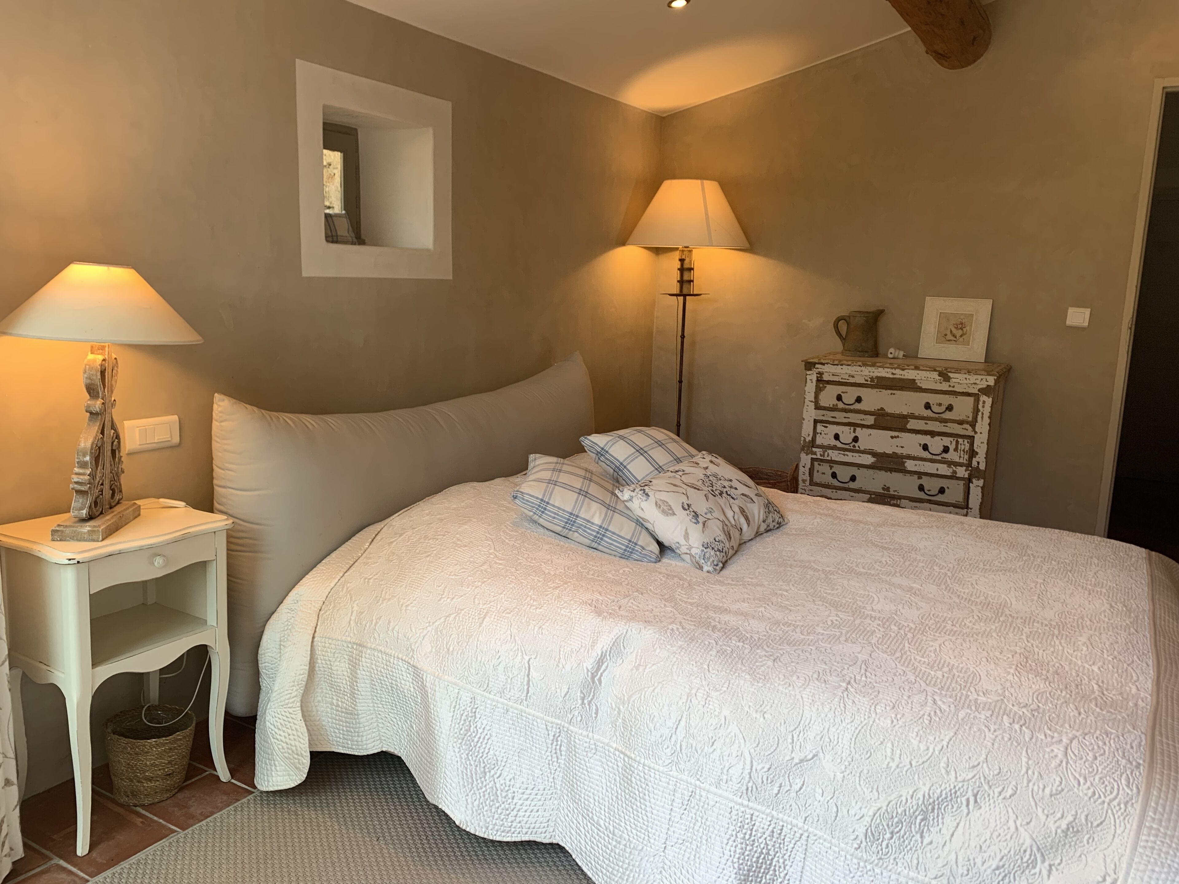 Un dormitorio con una cama grande, dos mesitas de noche con lámparas, un aparador y un espejo en la pared.