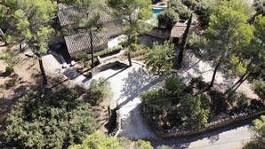 Una vista aerea di una proprietà con piscina, giardino a terrazze e un muro in pietra.