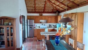 Una cocina con armarios de madera, un refrigerador de acero inoxidable, salpicadero de azulejos y una lámpara colgante.