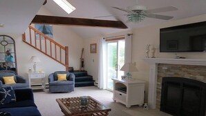 A living room with a fireplace, a television, a staircase, and a coffee table.