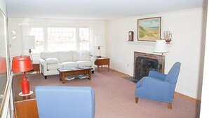 Una sala de estar con chimenea, paredes blancas y un sillón azul.