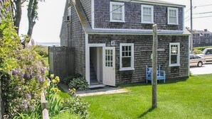 A two-story house with a front door, a small porch, and a grassy yard. - The Whistling Whale - Fantastic Location!! (Chatham)