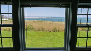 A view from a window with a grassy lawn and a body of water in the background. - The Whistling Whale - Fantastic Location!! (Chatham)