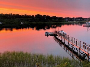 A calm lake at sunset with a wooden dock extending into the water. - Pet friendly, water views and lush lawns! (Chatham)