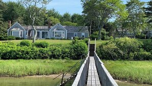 Un pont en bois qui mène à une rangée de maisons situées au bord d’un plan d’eau.