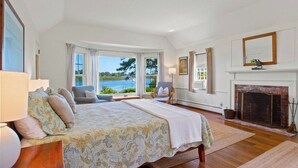 Une chambre spacieuse avec un grand lit, une cheminée et une vue sur la mer.