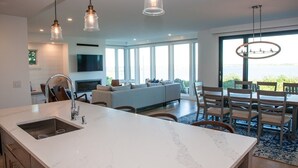A modern kitchen with a marble island, pendant lights, and a large window overlooking a scenic view.