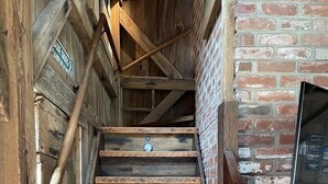 En trappe i træ med et rustikt design, omgivet af træbjælker og en murstensvæg.