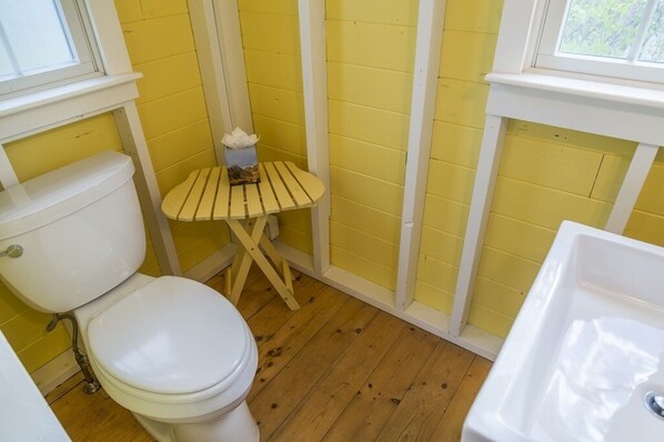 A small bathroom with a toilet, a sink, and a wooden stool.