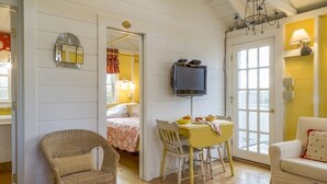 Una habitación acogedora con cama, una mesa de comedor con sillas, televisión y una silla de mimbre.