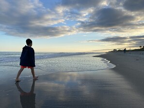 A beach scene with a child walking along the shore.